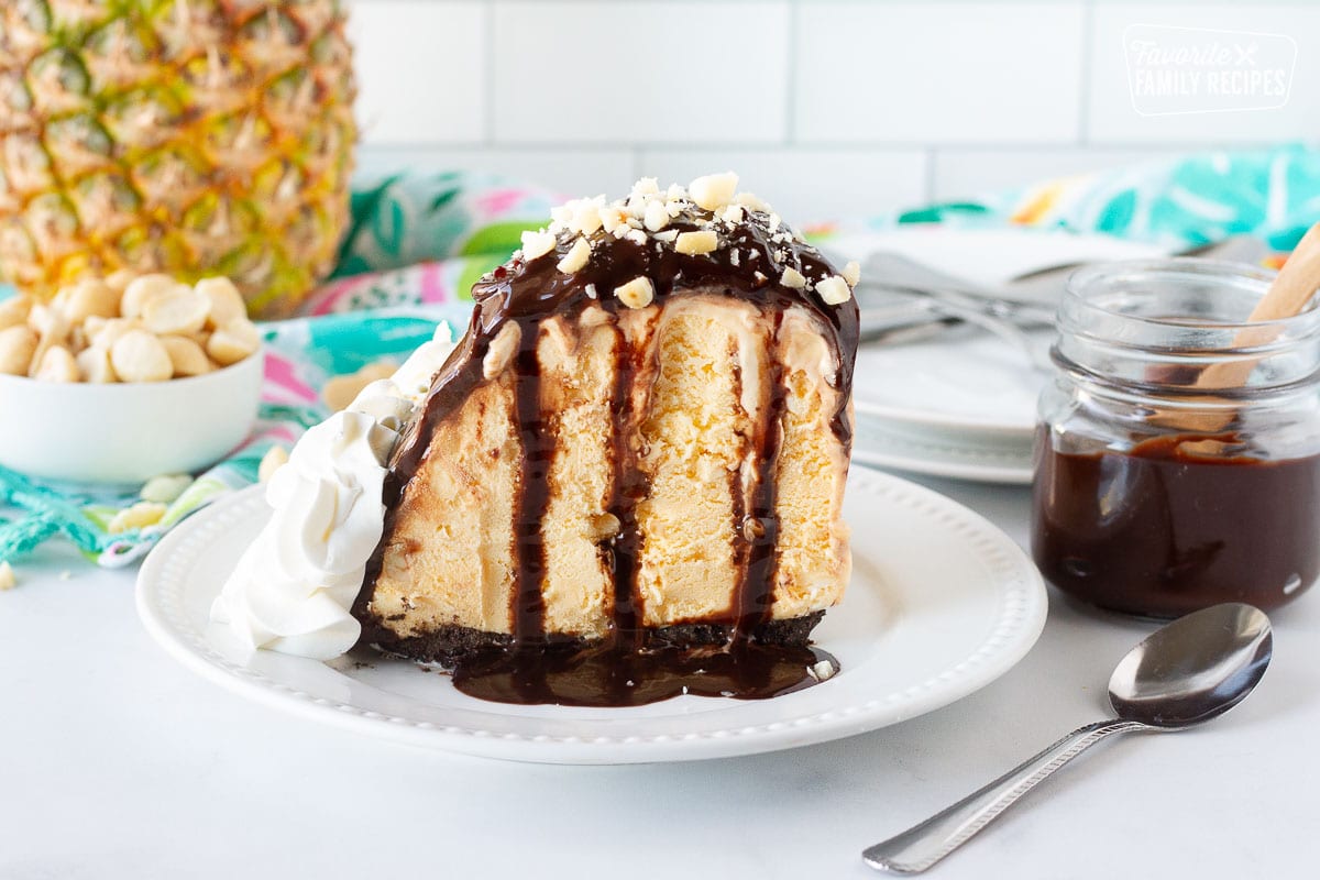 Plate with tall slice of Duke's Hula Pie. Macadamia nuts and fudge sauce on the side.