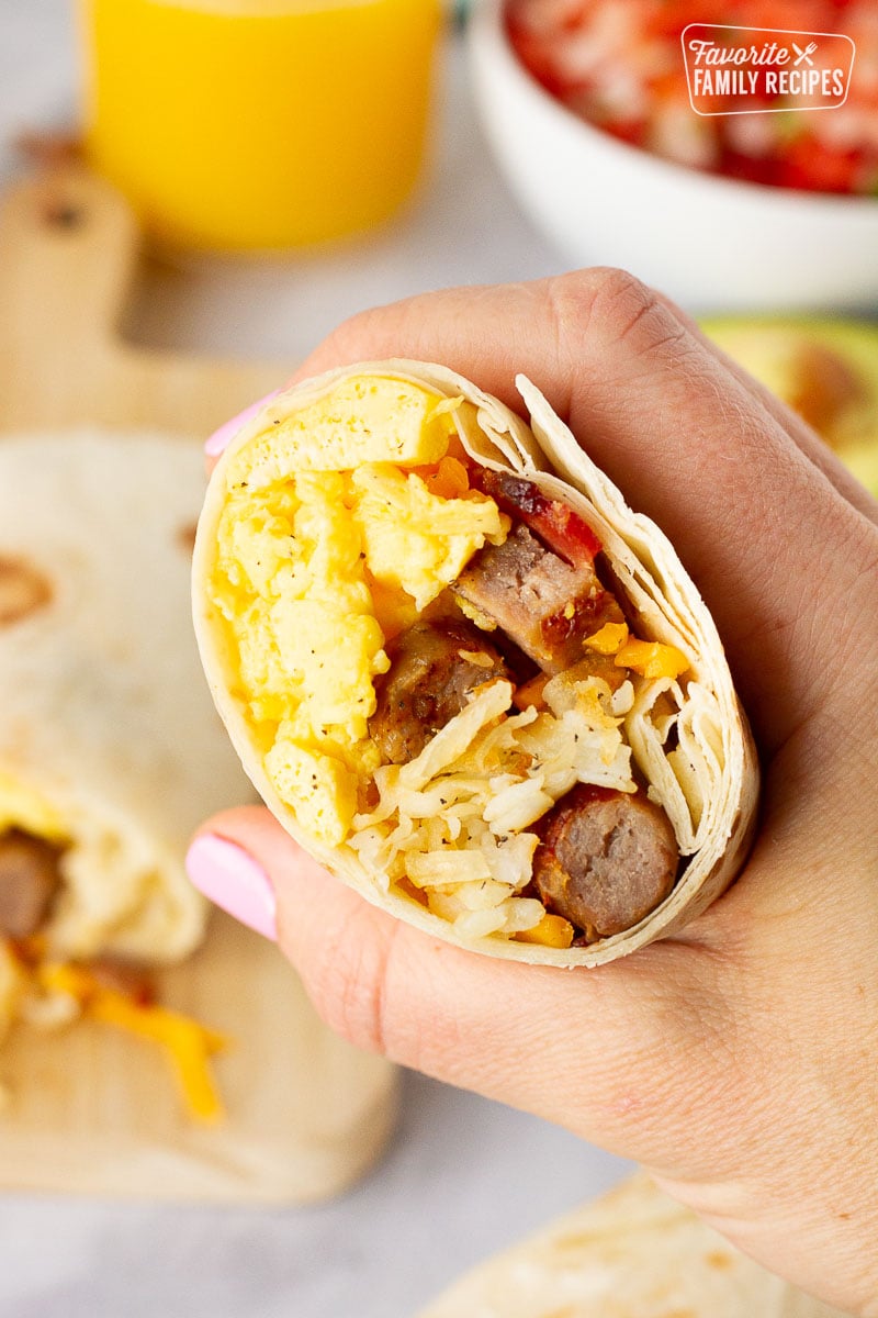 A hand holding a breakfast burrito to show filling