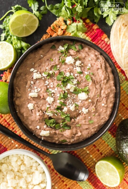 Homemade refried beans in a dish with cilantro and limes
