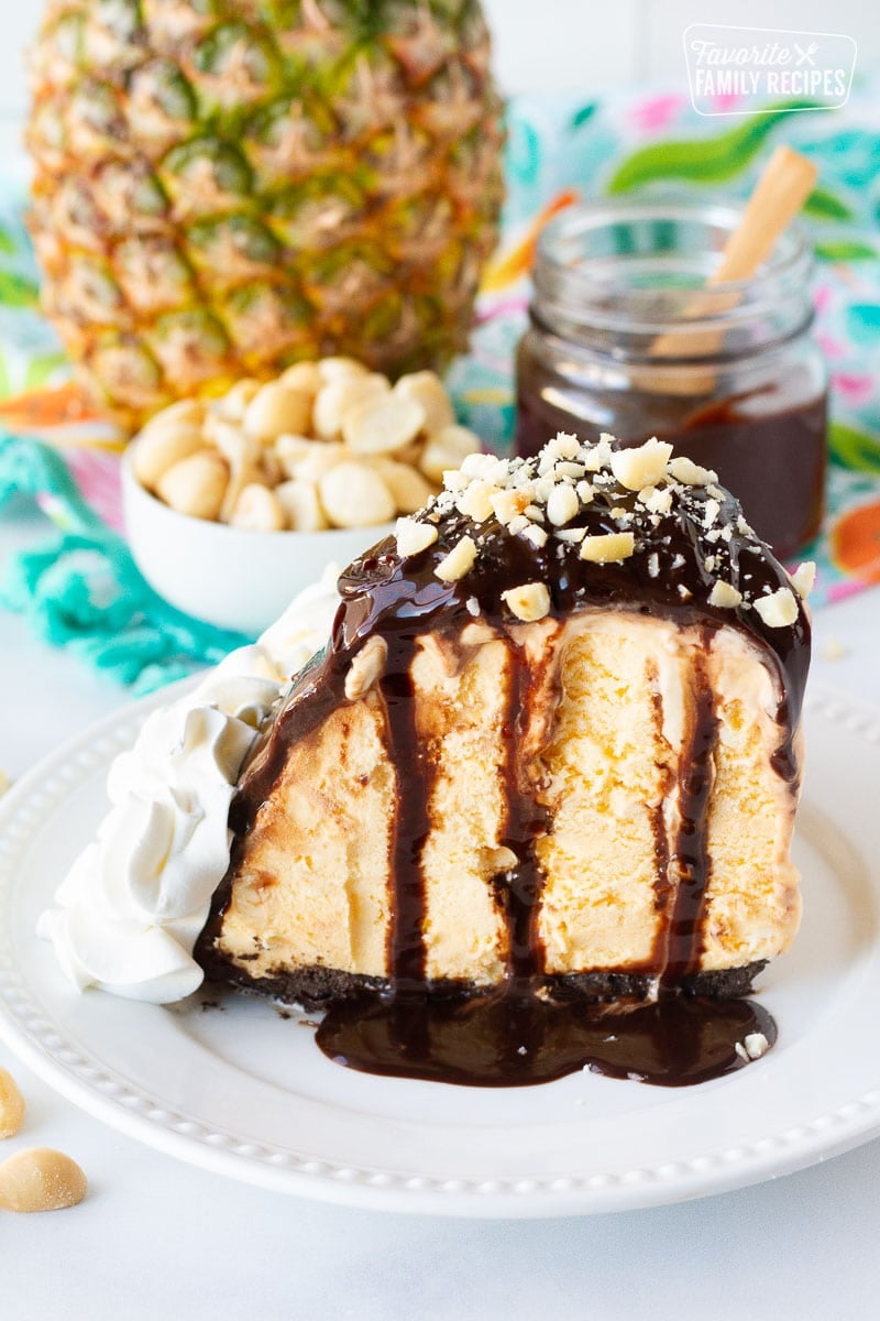 Duke's Hula Pie slice on a plate with fudge sauce and chopped macadamia nuts.