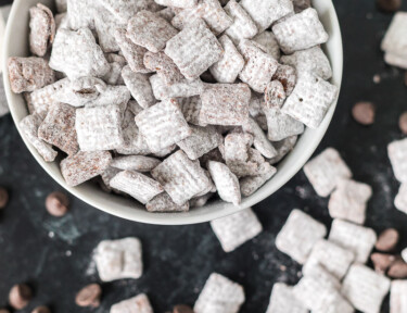 A bowl of muddy buddies on a black counter top