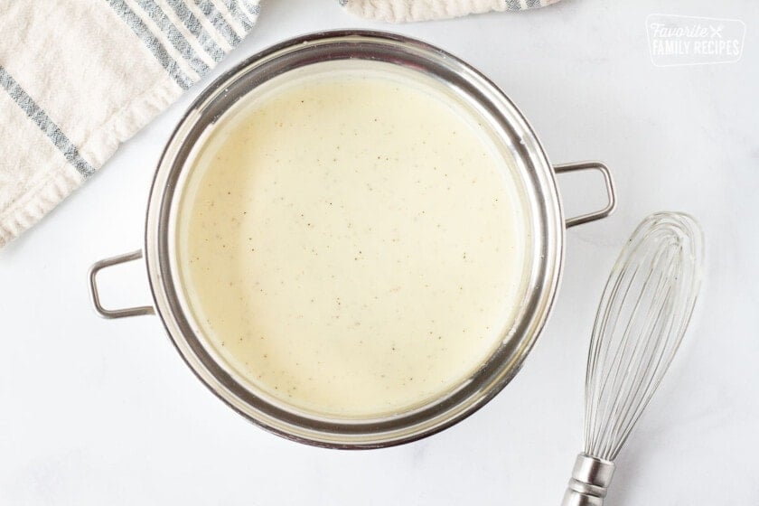 Pot of Chicken Cordon Bleu Sauce next to a whisk.