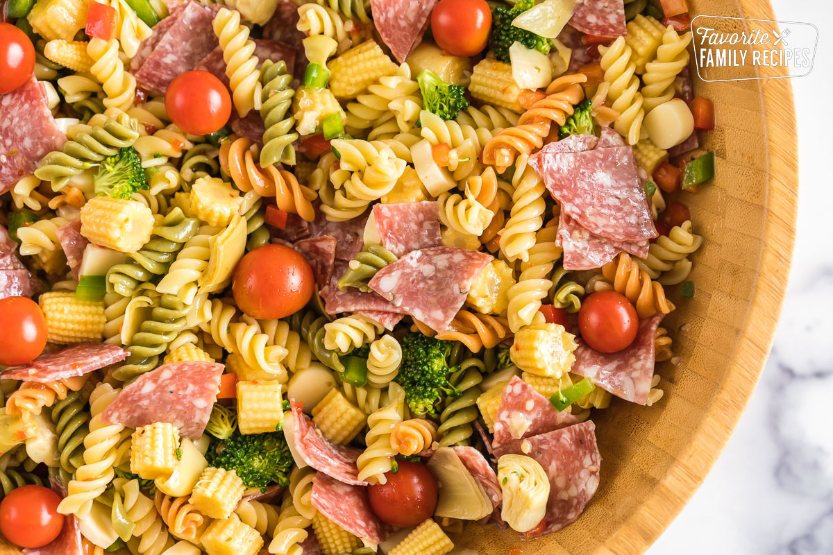 A large wooden bowl full of pasta salad with italian dressing