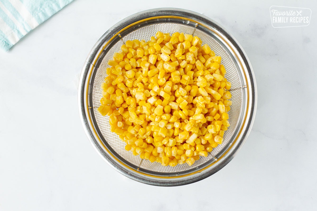 Colander of rinsed frozen corn to teach how to cook frozen corn.