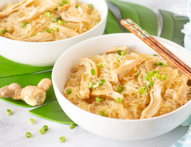 Side view of Hawaiian Style Chicken Long Rice Noodles in two bowls. Ginger and green onions on the side.