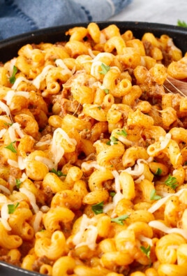 Creamy Ground Beef and Noodles in a skillet with a wooden spoon resting.