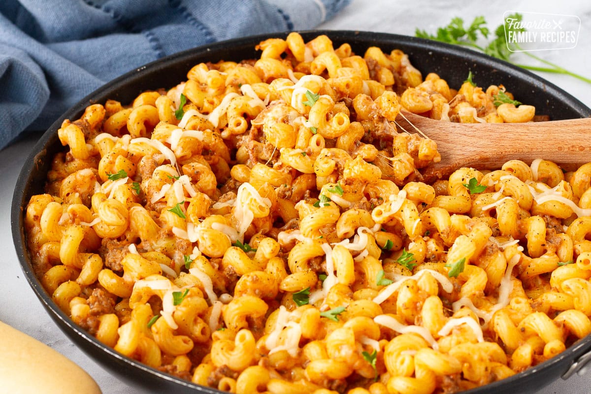 Creamy Ground Beef and Noodles in a skillet with a wooden spoon resting.