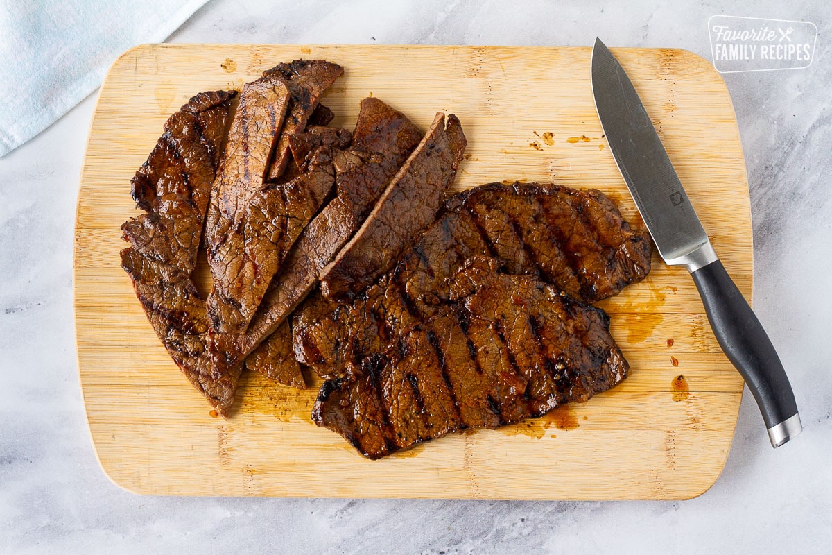Slicing the thin Hawaiian Beef Teriyaki steaks on a cutting board with a knife.