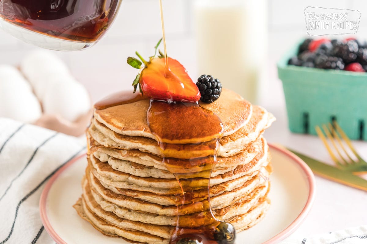 Syrup being poured on a stack of sourdough pancakes