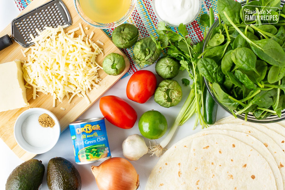 Cheese, spices, spinach, cilantro, tomatillos, spinach, broth, sour cream, green chilies, onion, garlic, pepper, tomatoes, avocados and flour tortillas to make Spinach Enchiladas.