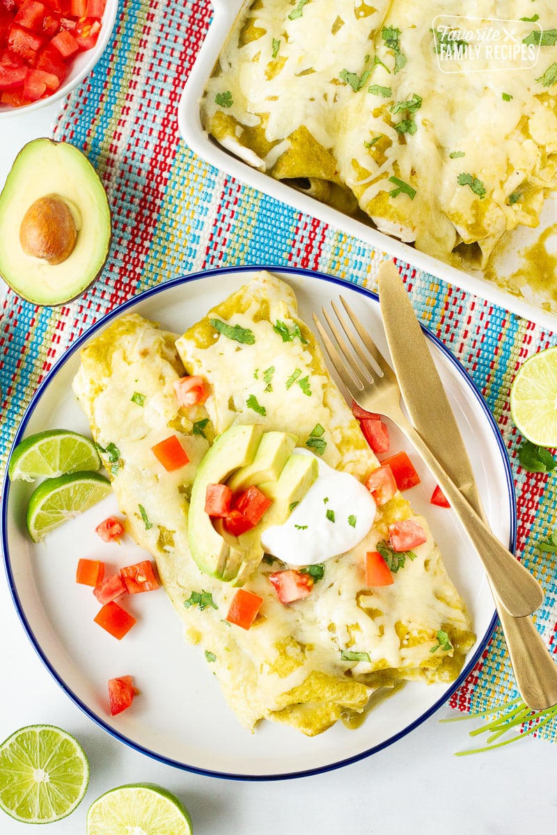 Plate of Spinach Enchiladas with avocados, cilantro, sour cream and tomatoes.