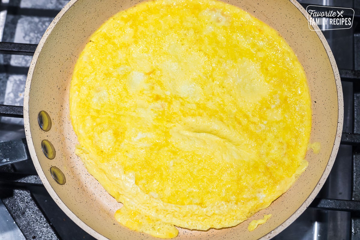 An omelette in a pan that has been flipped over and is ready to fill