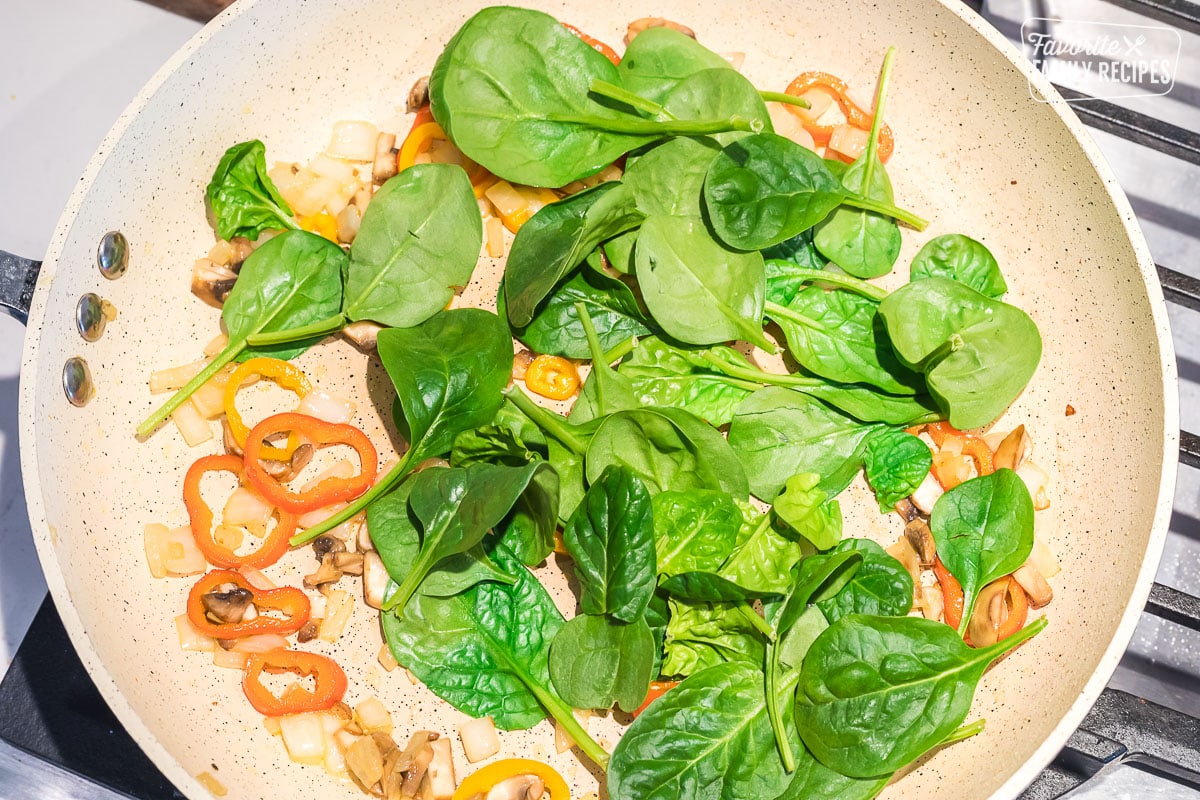 Spinach, peppers, onions, and mushrooms in a skillet