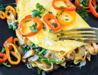 A fork breaking into a veggie omelette