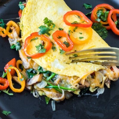 A fork breaking into a veggie omelette