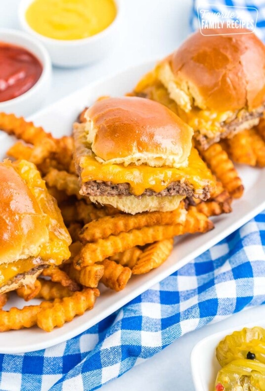 Three white castle sliders on a platter with french fries