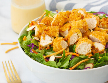 Applebee's Oriental Chicken Salad with dressing, linen and fork on the side.