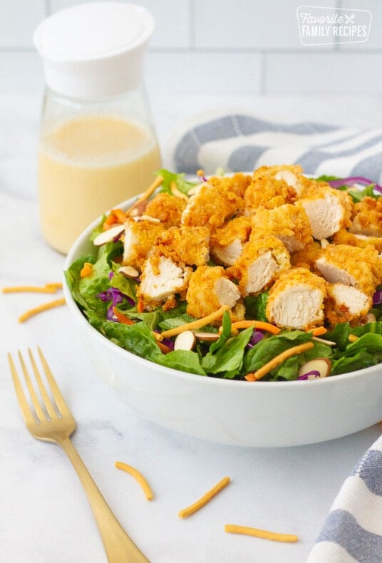 Applebee's Oriental Chicken Salad with dressing, linen and fork on the side.