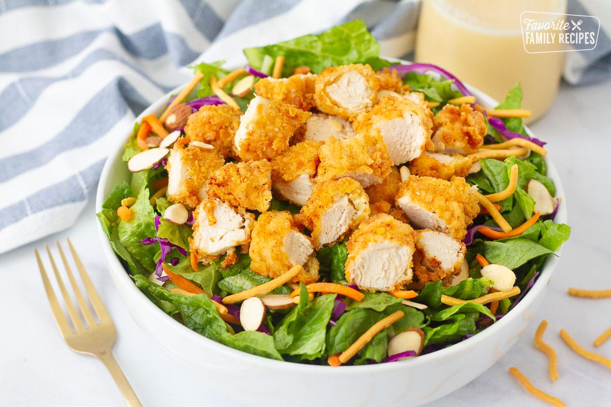 Bowl of Applebee's Oriental Chicken Salad with a bottle of homemade dressing on the side.
