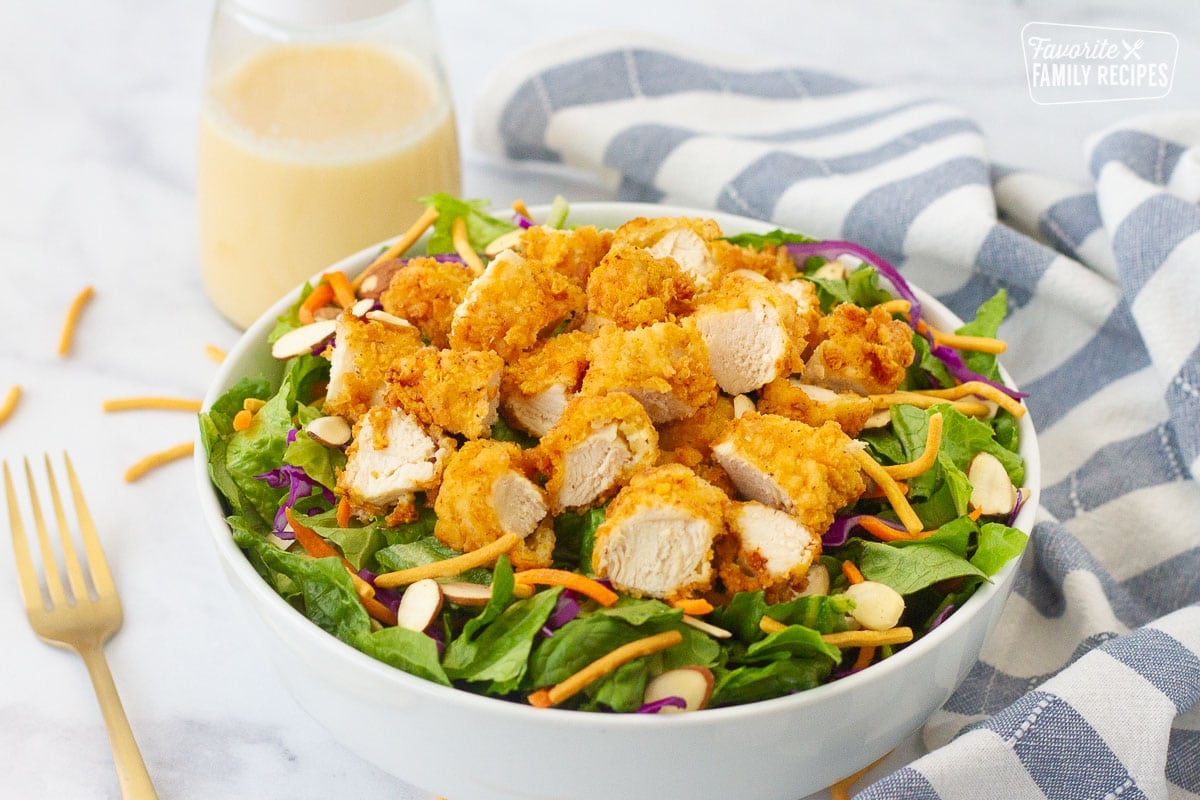 Applebee's Oriental Chicken Salad in a bowl with a fork and dressing on the side.