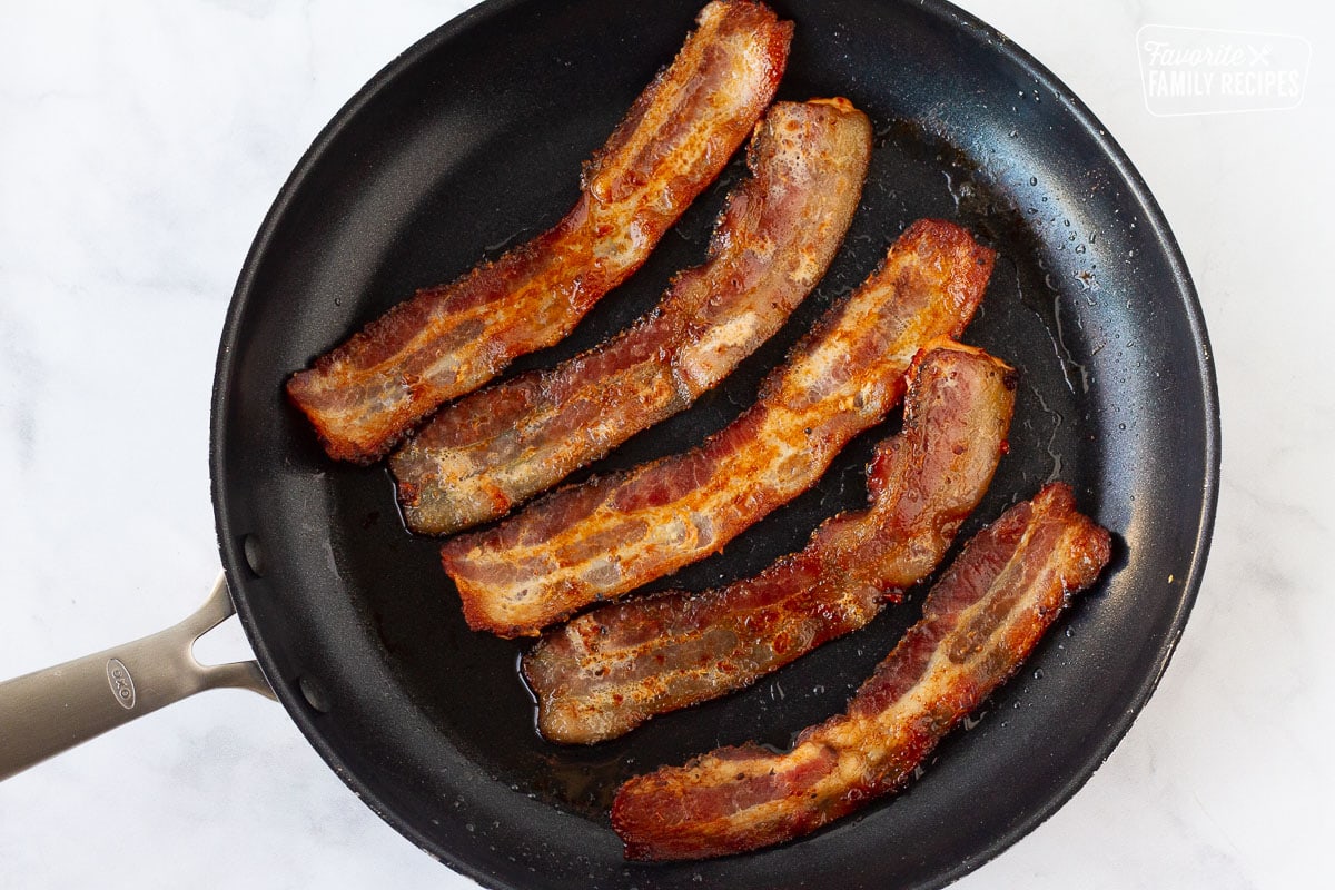 Frying pan with five strips of bacon for Grilled Chicken Sandwiches.