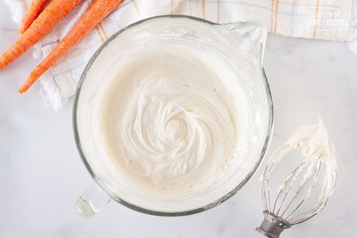 Mixing bowl with cream cheese frosting for Carrot Cake Cookies. Mixing whisk on the side.