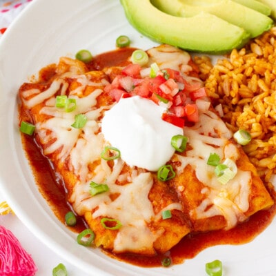 Plate of Easy Cheese Enchiladas with rice, avocado and sour cream on top.