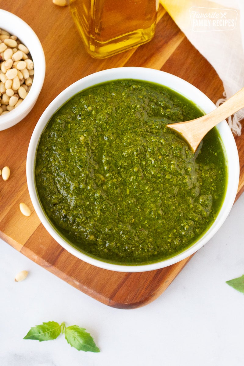 Bowl of fresh Homemade Pesto with pine nuts and olive oil on the side.