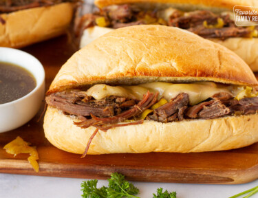 Close up of an Italian Beef Sandwich on a lightly toasted bun and melted pepper jack cheese.