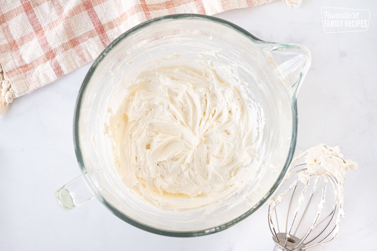 Mixing bowl with cream cheese and butter mixed for Cream Cheese Frosting. Mixing whisk on the side.