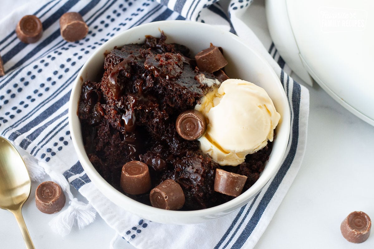 Bowl of Crockpot Lava Cake with extra Rolos and vanilla ice cream next to the Crockpot.