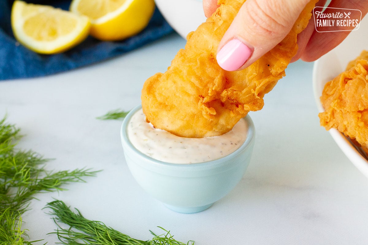 Dipping battered fish into a small sauce bowl of Homemade Tartar Sauce.