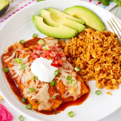 Plate of two Easy Cheese Enchiladas with sliced avocado, rice, sour cream and pico.