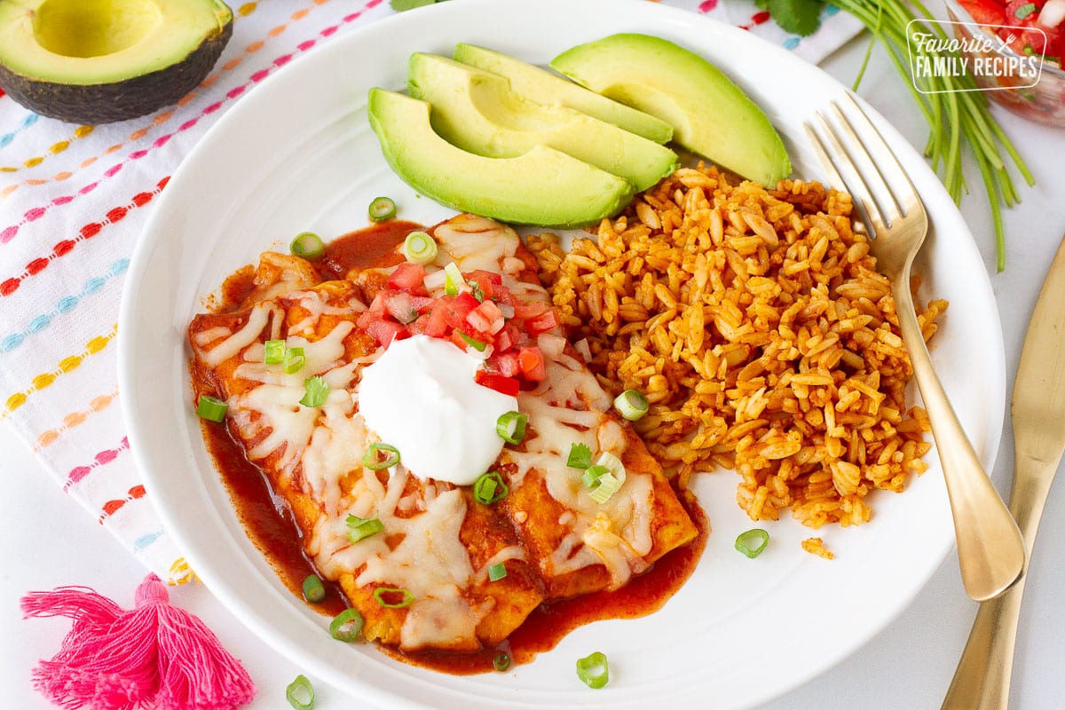 Plate of two Easy Cheese Enchiladas with sliced avocado, rice, sour cream and pico.