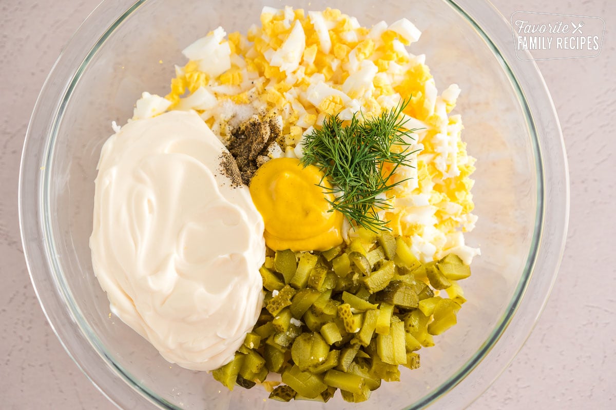 Hard boiled eggs, mayo, mustard, pickles, salt, pepper, and dill all in a large bowl
