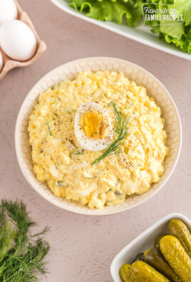 Egg salad in a bowl topped with half of a hard boiled egg and a sprig of dill