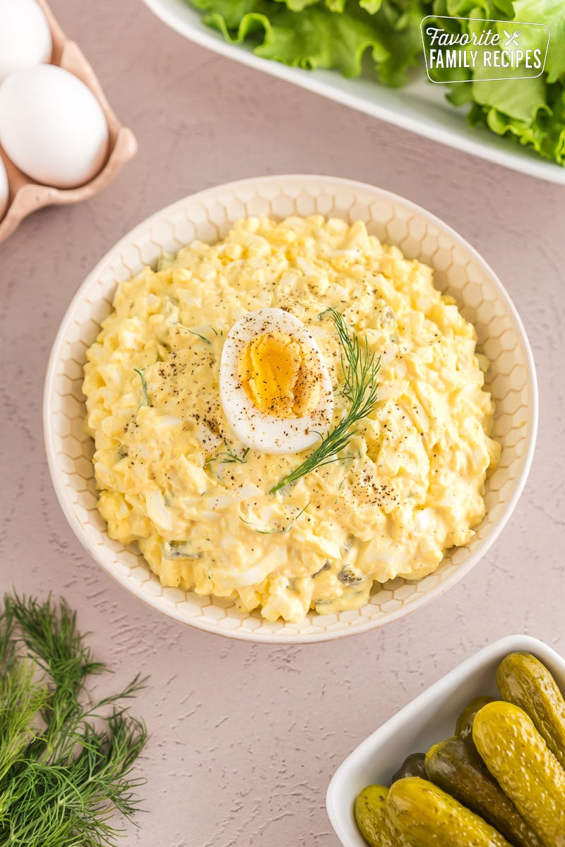 Egg salad in a bowl topped with half of a hard boiled egg and a sprig of dill