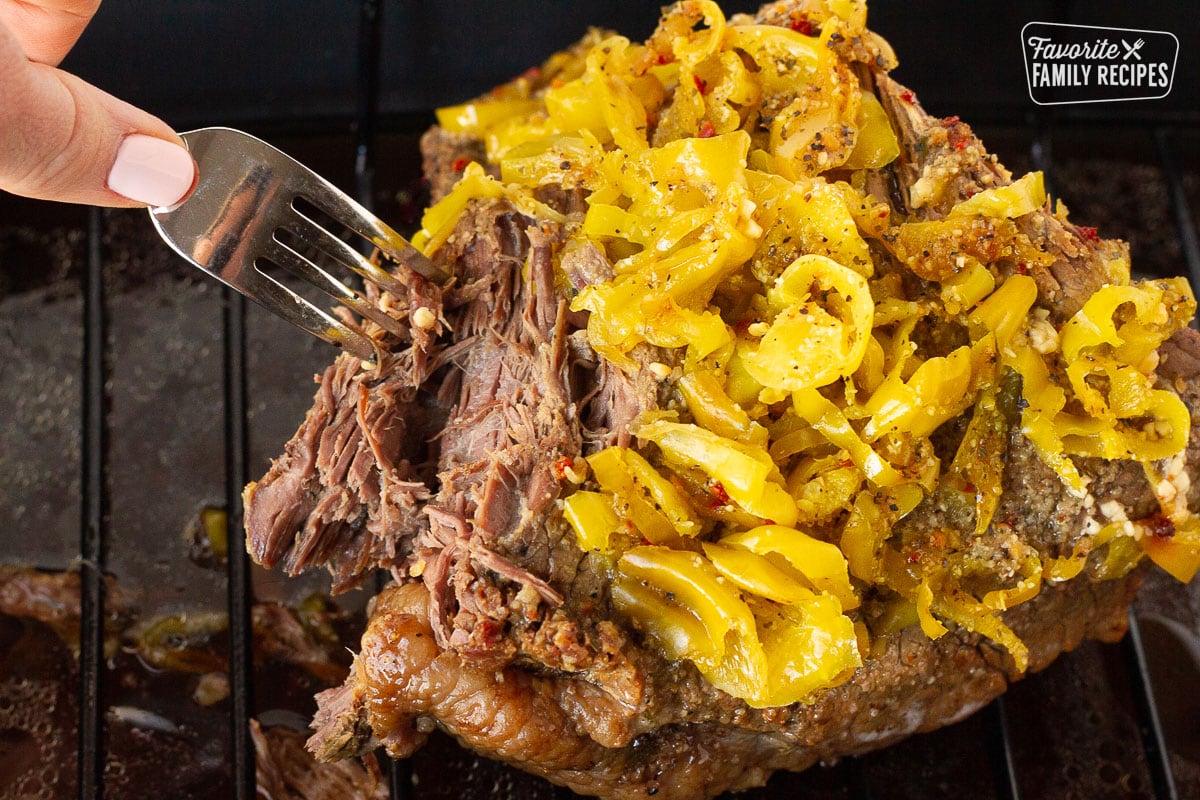 Fork shredding the cooked beef roast for Italian Beef Sandwiches.