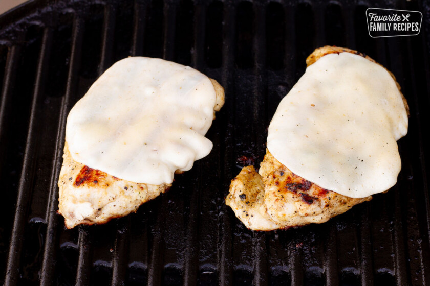 Grilled Chicken on a barbecue with provolone cheese melting on top for Sandwiches.