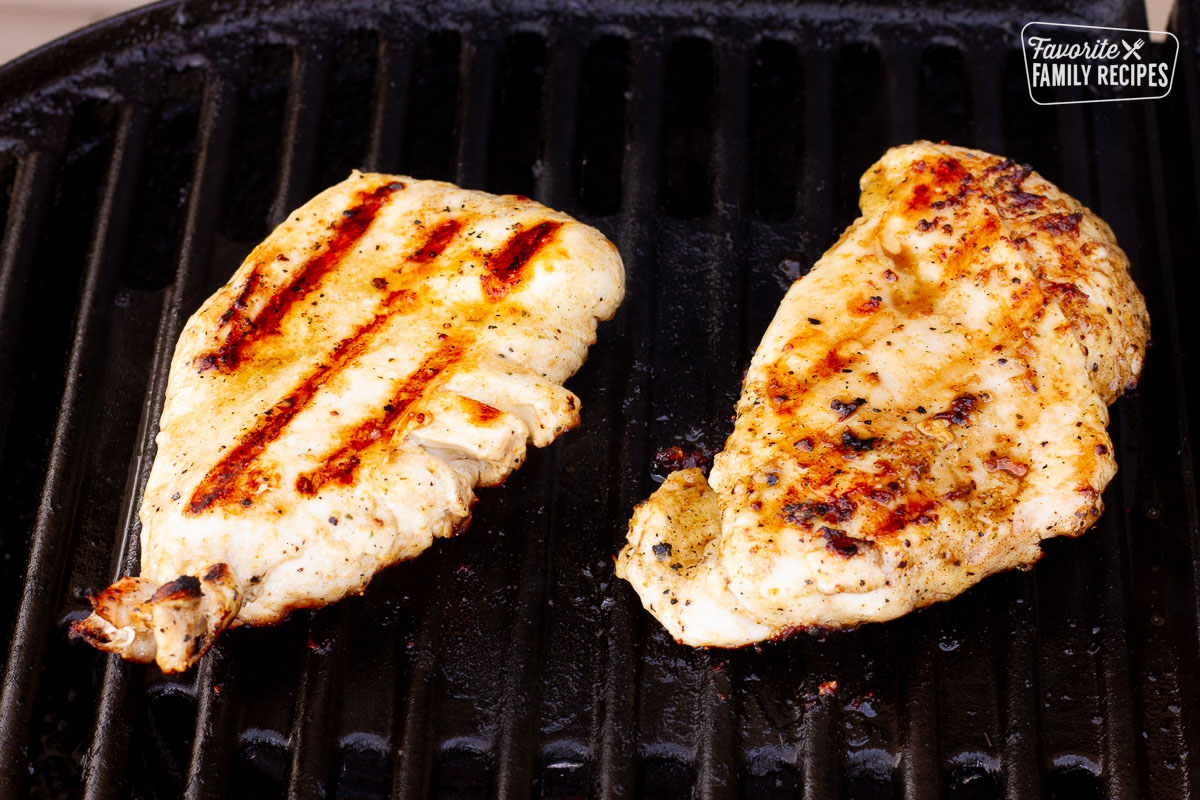 Grilling chicken on a barbecue for Grilled Chicken Sandwiches.
