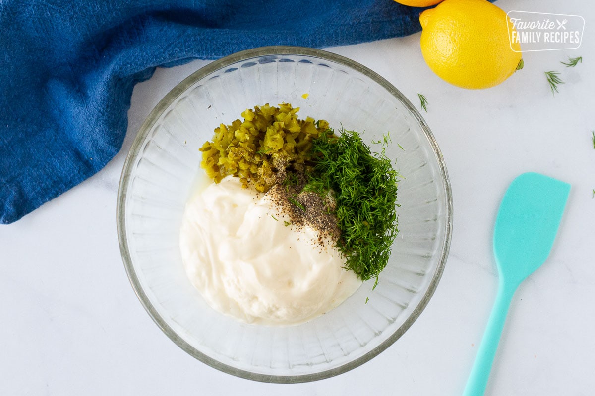 Bowl of mayonnaise, pickles, dill, pepper and lemon juice for making Homemade Tartar Sauce.