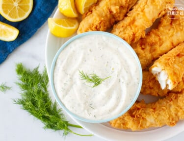 Plate with battered fish with lemons and a large bowl of Homemade Tartar Sauce.