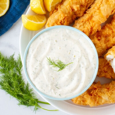 Plate with battered fish with lemons and a large bowl of Homemade Tartar Sauce.