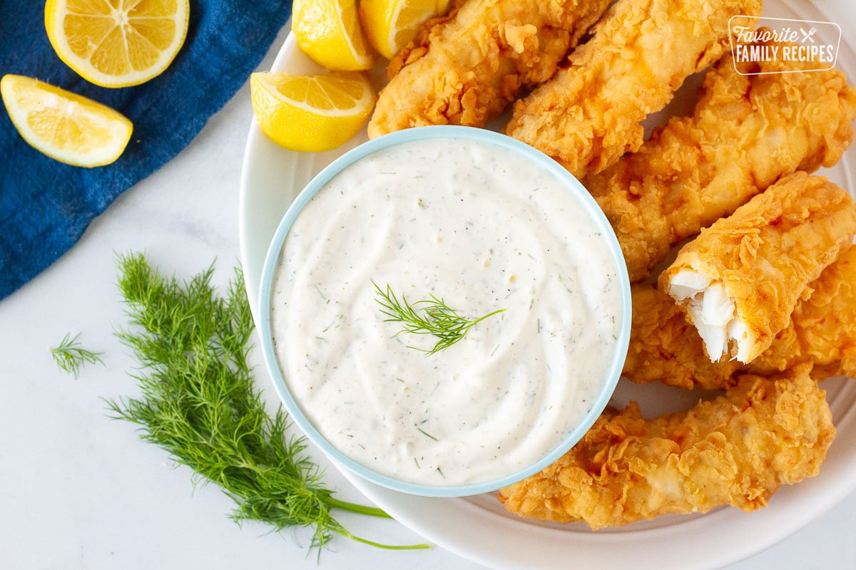 Plate with battered fish with lemons and a large bowl of Homemade Tartar Sauce.