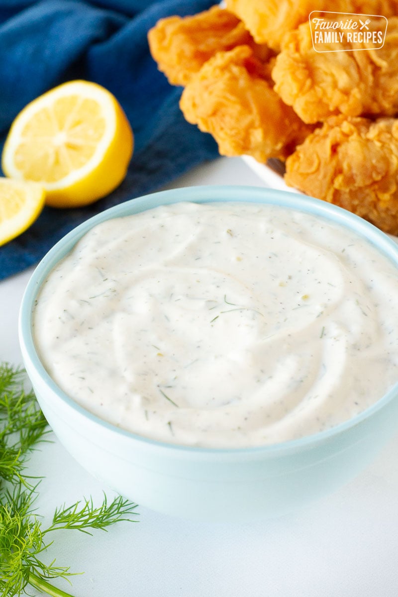 Bowl of Homemade Tartar Sauce in front of a plate of battered fish and lemon.