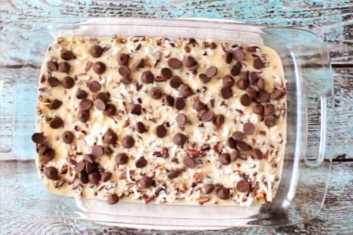 Ingredient mixture and chocolate chips spread over German Chocolate Cookie Bars.