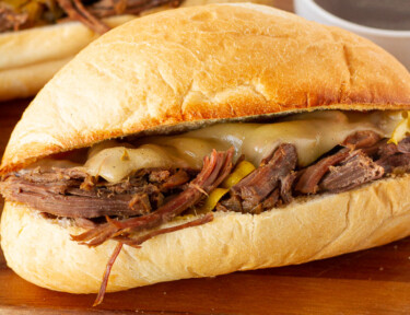 Two Italian Beef Sandwiches with au jus. Parsley on the side for garnish.