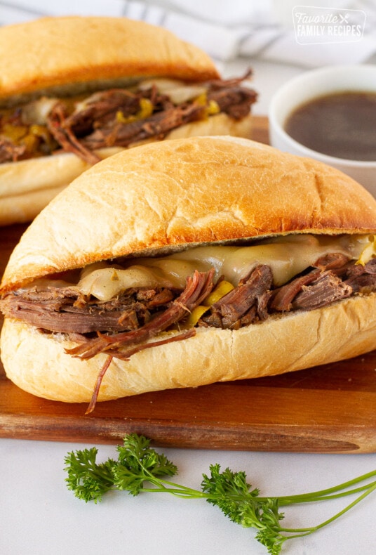 Two Italian Beef Sandwiches with au jus. Parsley on the side for garnish.