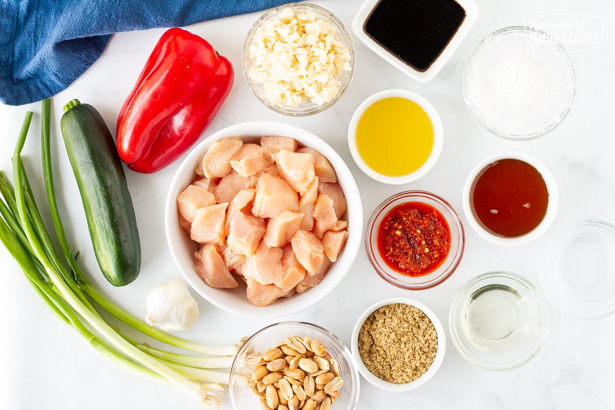 Ingredients for Kung Pao Chicken including red pepper, zucchini, green onions, peanuts, brown sugar, water chestnuts, chicken broth, sesame oil, soy sauce, chili paste, corn starch, vegetable oil and vinegar.