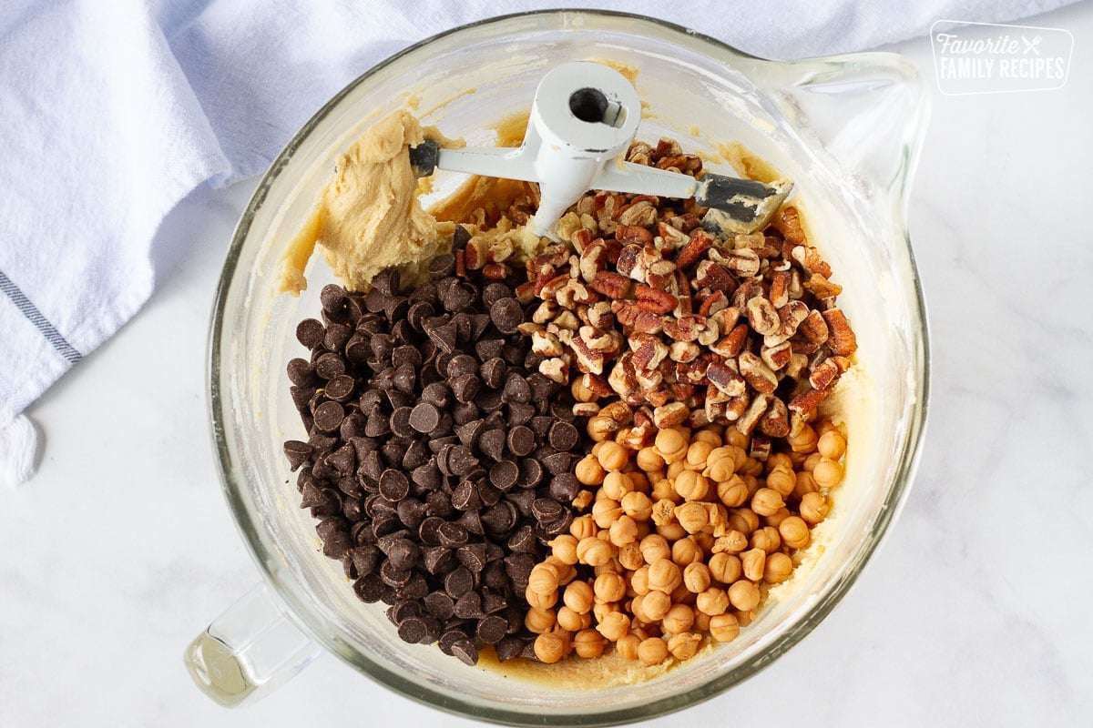 Mixing bowl with Turtle cookie dough with pecans, chocolate chips and caramel bits on top.